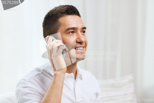 Image of happy man calling on smartphone at home