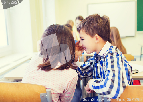 Image of smiling schoolgirl whispering to classmate ear