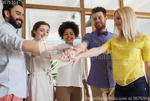 Image of happy creative team ith hands on top in office