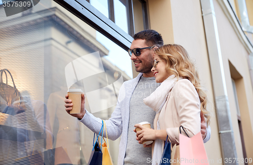 Image of happy couple with shopping bags and coffee in city