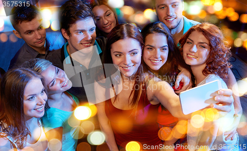 Image of friends with smartphone taking selfie in club