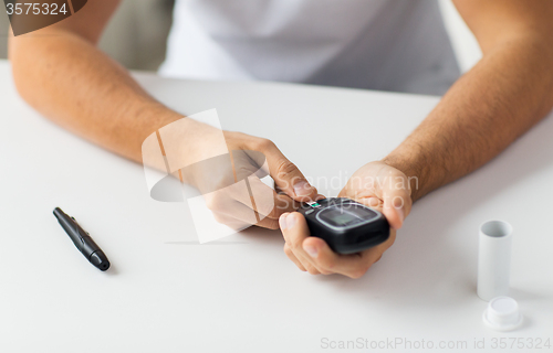 Image of close up of man checking blood sugar by glucometer