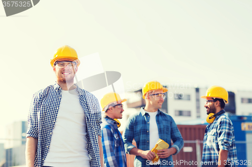 Image of group of smiling builders in hardhats outdoors