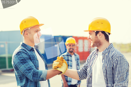 Image of group of smiling builders in hardhats outdoors