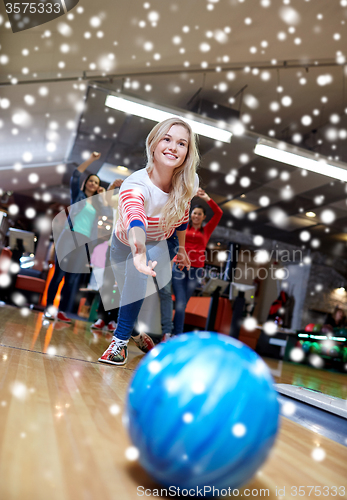 Image of happy young woman throwing ball in bowling club