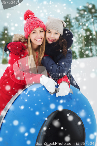 Image of happy girl friends with snow tubes outdoors