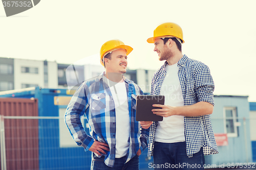 Image of smiling builders in hardhats with tablet pc