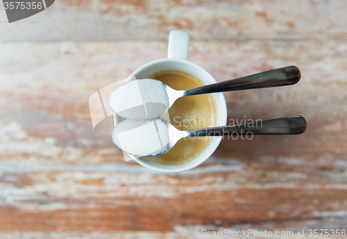 Image of close up of white sugar on teaspoon and coffee cup