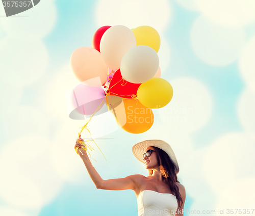 Image of smiling young woman in sunglasses with balloons