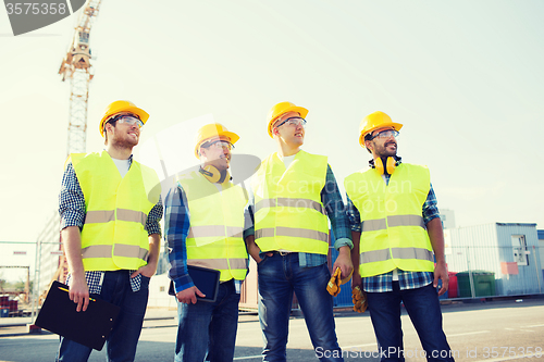 Image of group of smiling builders with tablet pc outdoors