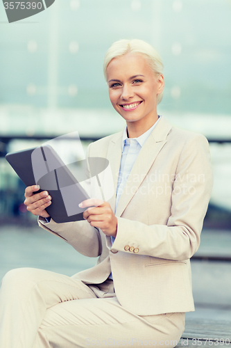 Image of smiling businesswoman with tablet pc outdoors