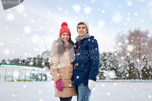 Image of happy couple ice skating on rink outdoors