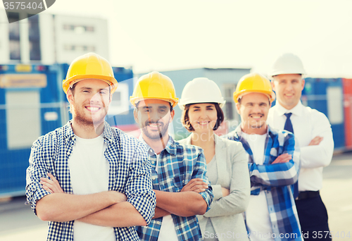 Image of group of smiling builders in hardhats outdoors