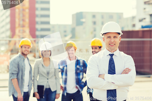 Image of group of smiling builders in hardhats outdoors