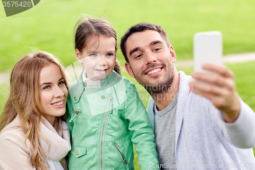 Image of happy family taking selfie by smartphone outdoors