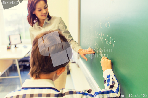 Image of school boy with teacher writing on chalk board