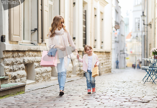 Image of happy mother and child with shopping bags in city