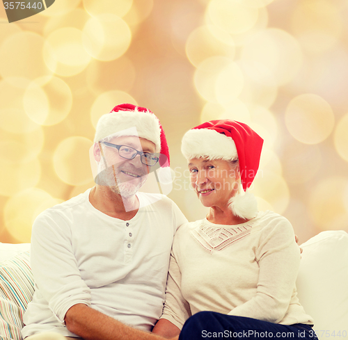 Image of happy senior couple in santa helper hats