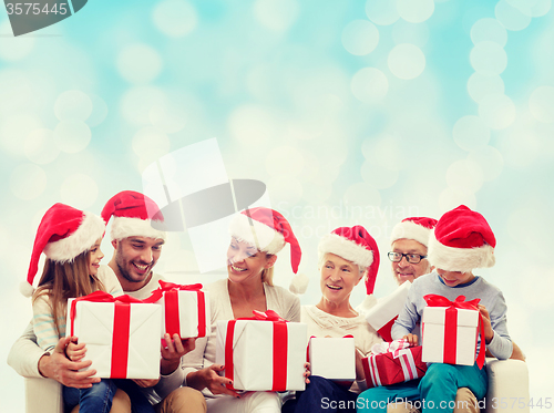 Image of happy family in santa helper hats with gift boxes