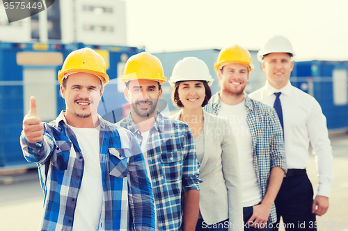 Image of group of smiling builders in hardhats outdoors