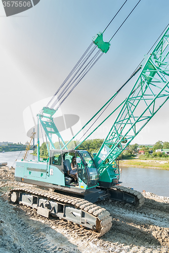 Image of Attractive girl controls construction crane