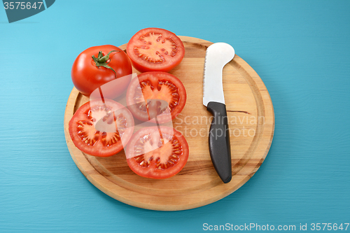 Image of Whole tomato and halves with tomato knife 