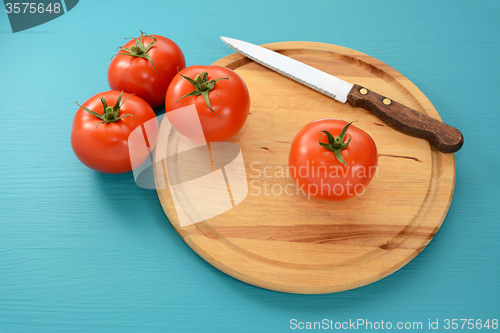 Image of Tomatoes with a serrated knife on a wooden board