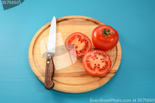 Image of Whole and halved tomato with kitchen knife