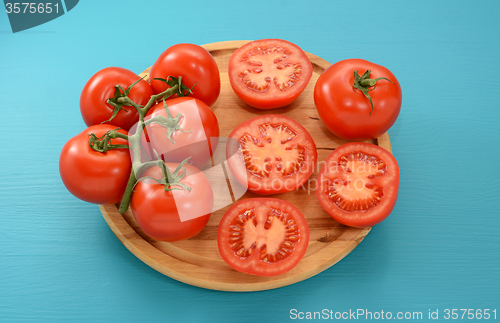 Image of Tomatoes - on the vine, halved and whole on a wooden board