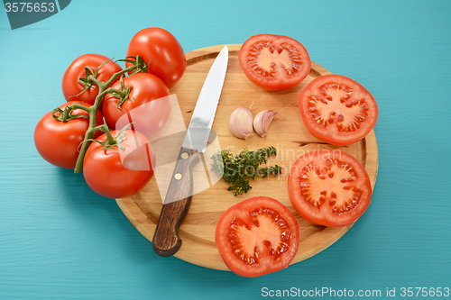 Image of Tomatoes cut for roasting with knife, garlic and thyme