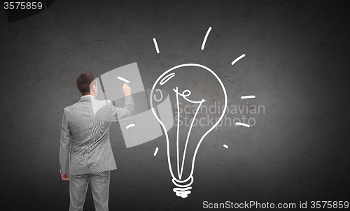 Image of businessman drawing lighting bulb from back