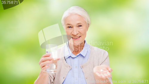 Image of happy senior woman with water and medicine