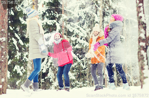 Image of group of happy friends playing snowballs in forest