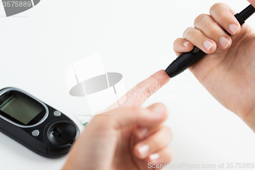 Image of close up of woman making blood test by glucometer