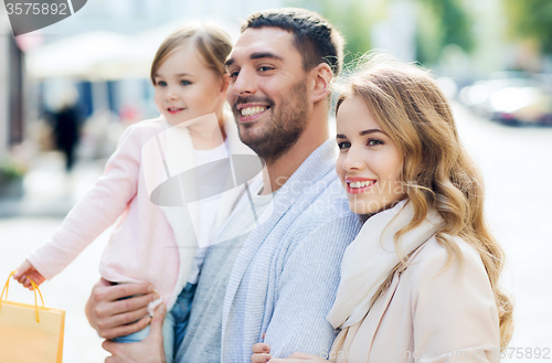 Image of happy family with child and shopping bags in city