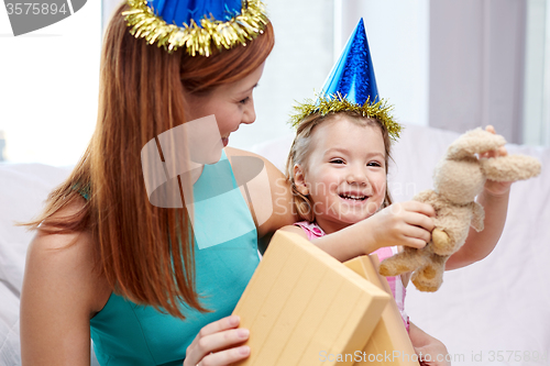 Image of happy mother and little girl with gift at home