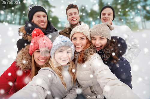 Image of group of smiling friends taking selfie outdoors