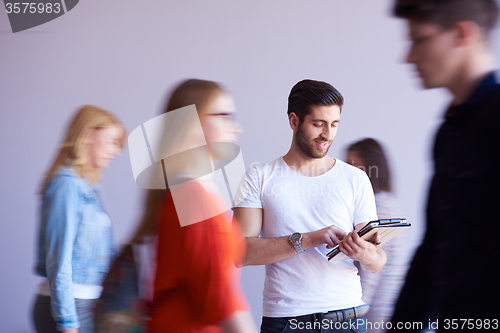 Image of student working on tablet, people group passing by