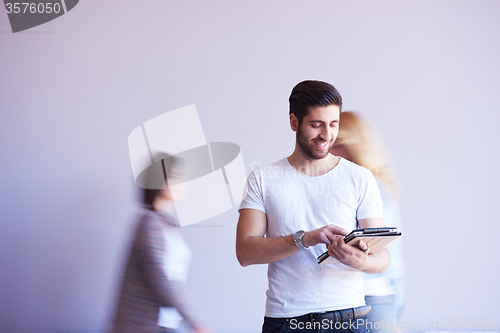 Image of student working on tablet, people group passing by