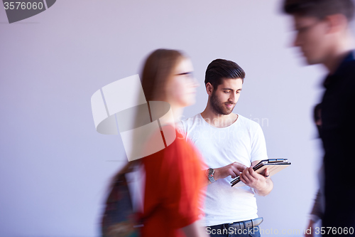 Image of student working on tablet, people group passing by