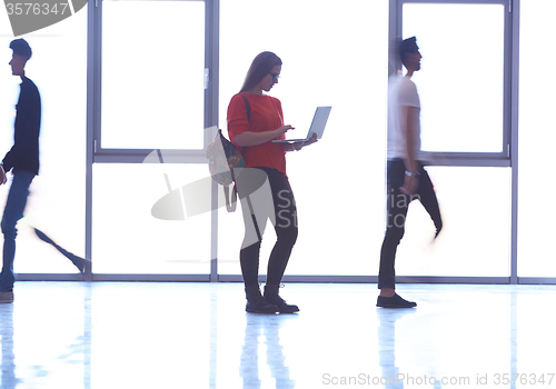 Image of student girl standing with laptop, people group passing by