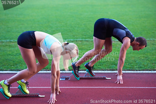 Image of woman group  running on athletics race track from start