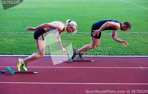 Image of woman group  running on athletics race track from start