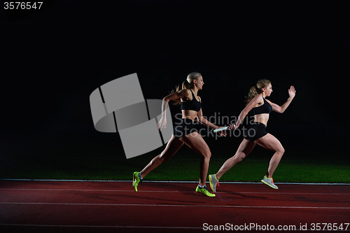 Image of athletic runners passing baton in relay race