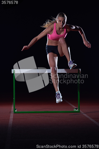 Image of woman athlete jumping over a hurdles