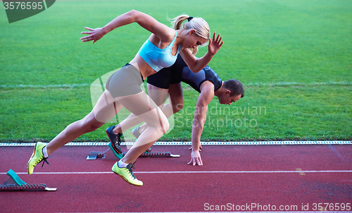 Image of woman group  running on athletics race track from start