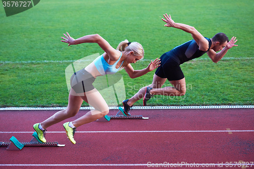 Image of woman group  running on athletics race track from start