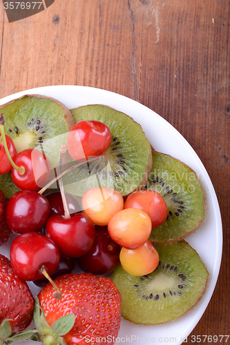 Image of health fruit with cherry, strawberry, kiwi on wooden plate