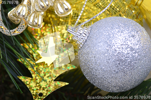 Image of festive golden christmas decoration, candles, white balls, green fir tree branch, close up