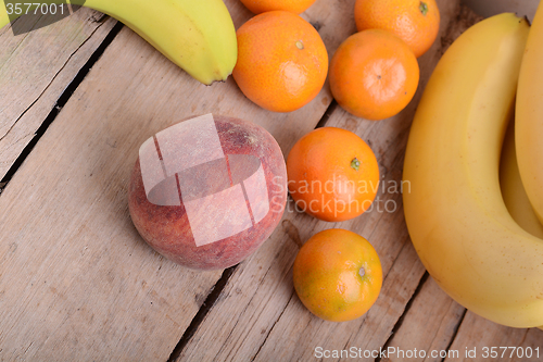 Image of Bananas apple mandarin peach strawberry on wooden background as health food concept